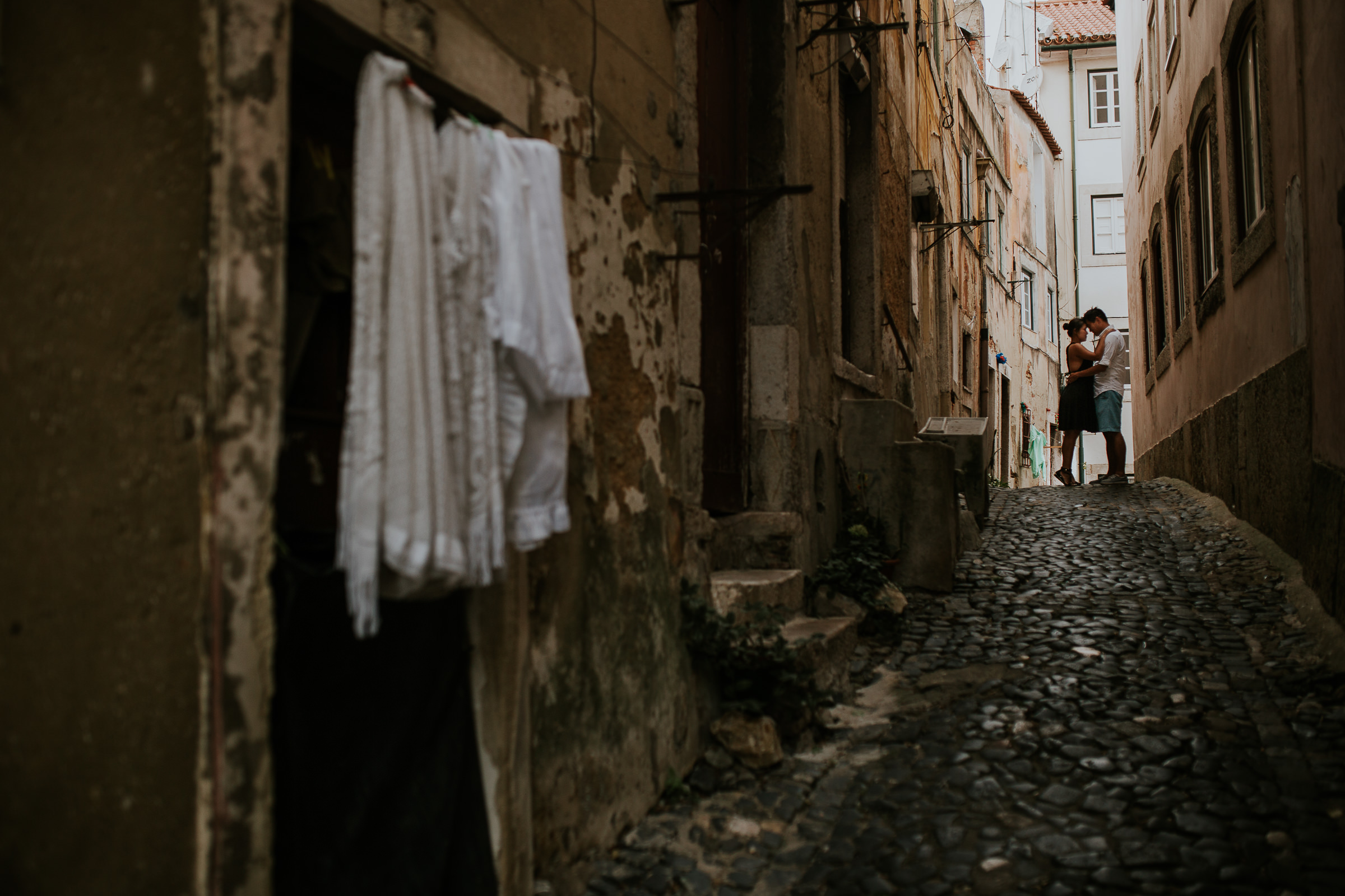 couple embraced in lisbon streets with clothesline