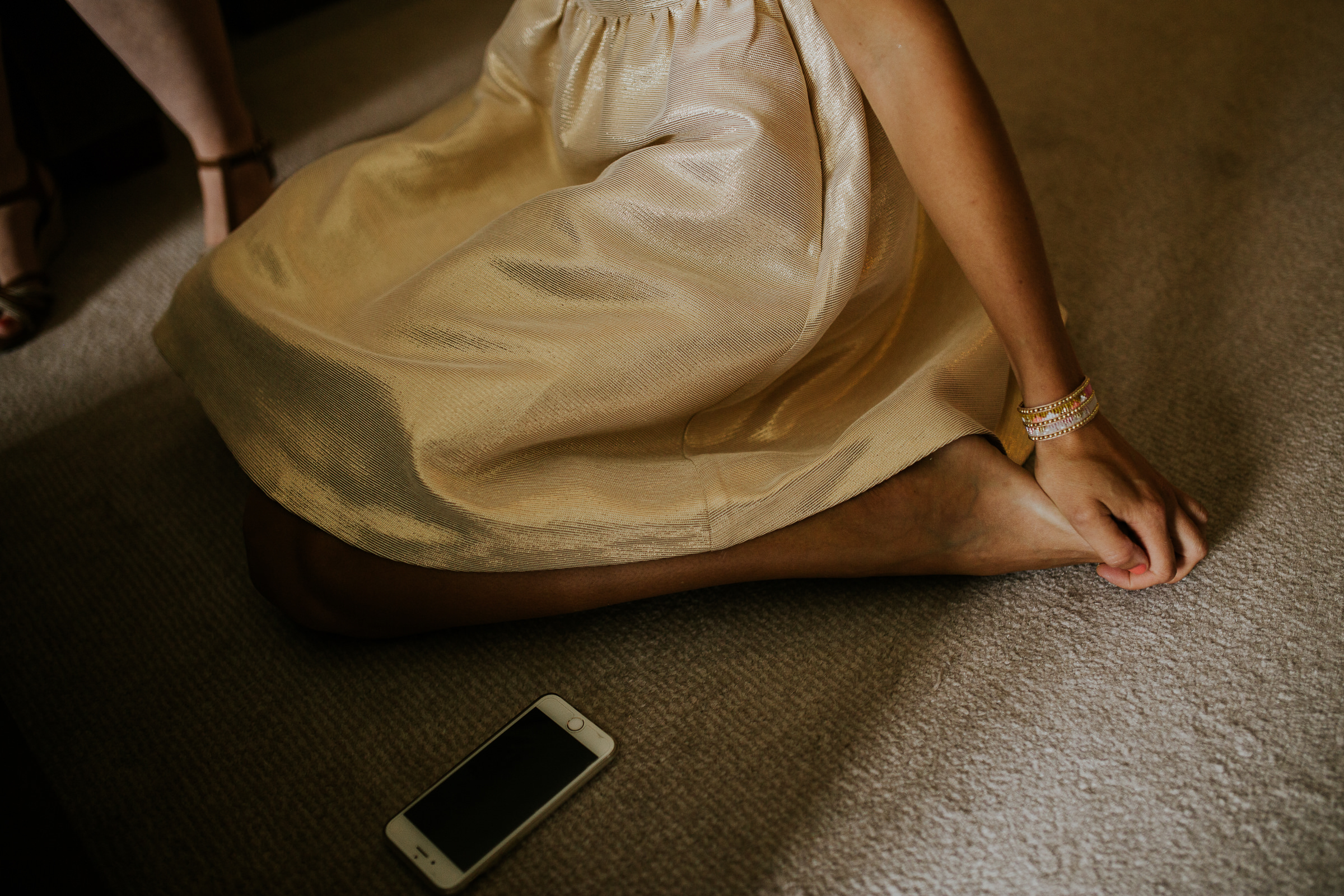 Detail of a bridesmaid dress foot and hand on a carpet floor