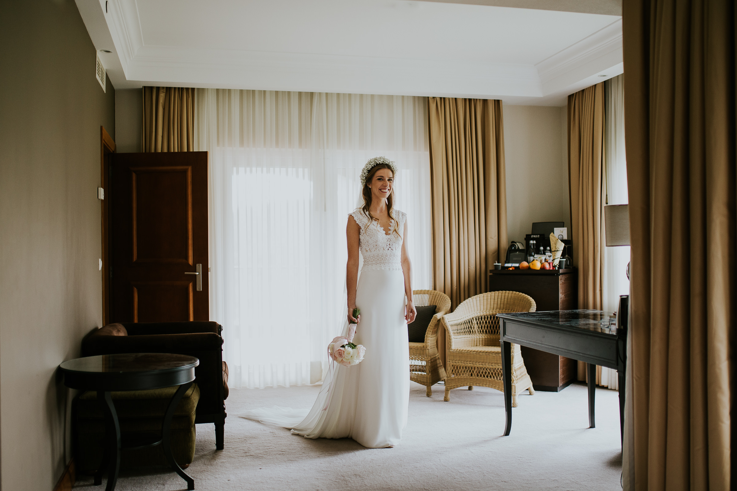 Centered portrait of the bride holing her bouquet in the middle of an hotel room